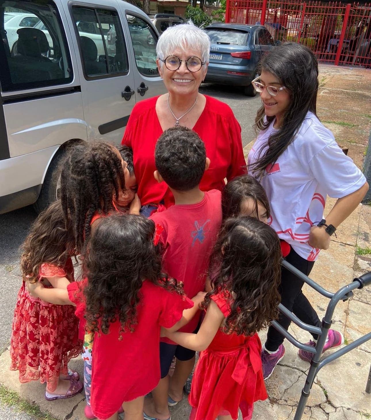 Vicky Tavares, de vermelho, rodeada por crianças acolhidas pelo Instituto em frente à sede.